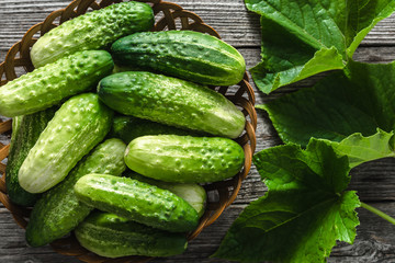 Basket with cucumbers, fresh vegetables - organic produce on wooden background