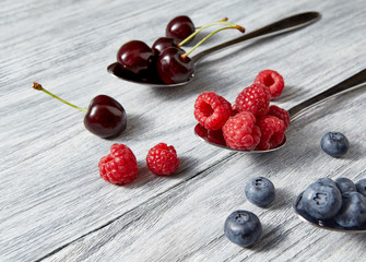 Delicious juicy berries on a spoon gray wooden background. Flat lay. Concept of vegetarian eating.