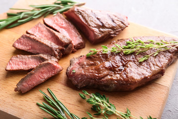 Tasty grilled meat with herbs on wooden board