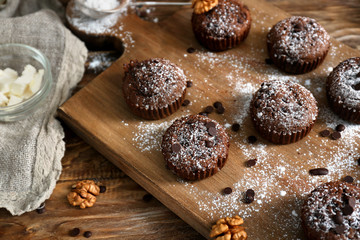 Board with tasty chocolate muffins on wooden table