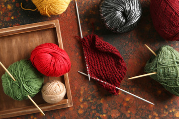 Colorful knitting yarn with unfinished clothes on table