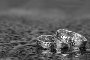 Wedding rings with water drops on grey background with copy space.