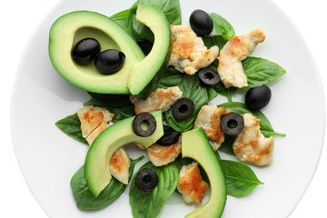 Salad with ripe avocado on plate against white background, closeup