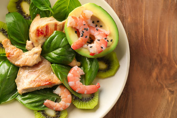 Plate with tasty avocado salad on wooden table, closeup