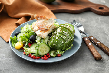 Plate with tasty avocado salad on table