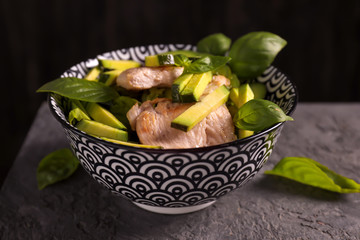 Bowl with tasty avocado salad on dark table