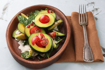 Plate with tasty avocado salad on table