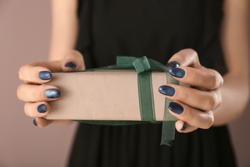 Young woman with beautiful manicure holding gift box, closeup