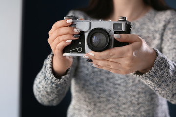 Young woman with beautiful manicure and retro photo camera on dark background, closeup