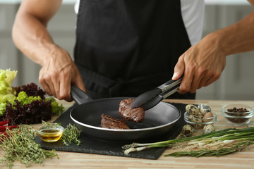 Obraz na płótnie Canvas Man preparing delicious meat with fresh spices in kitchen