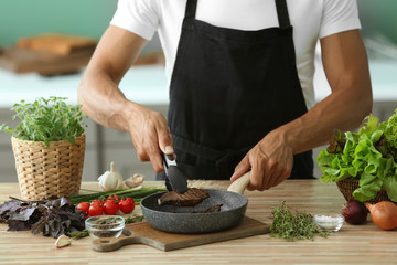 Man preparing delicious meat with fresh spices in kitchen