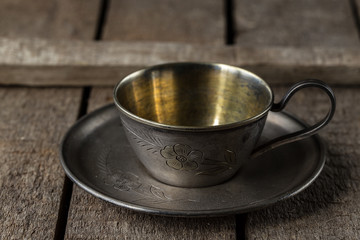 old  metal cup for coffee on a saucer