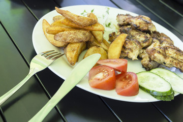 salad of vegetables, grilled meat on a white plate on a black background, photo menu.