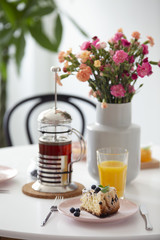 Flowers and orange juice on table with tea and dessert in the restaurant interior. Real photo