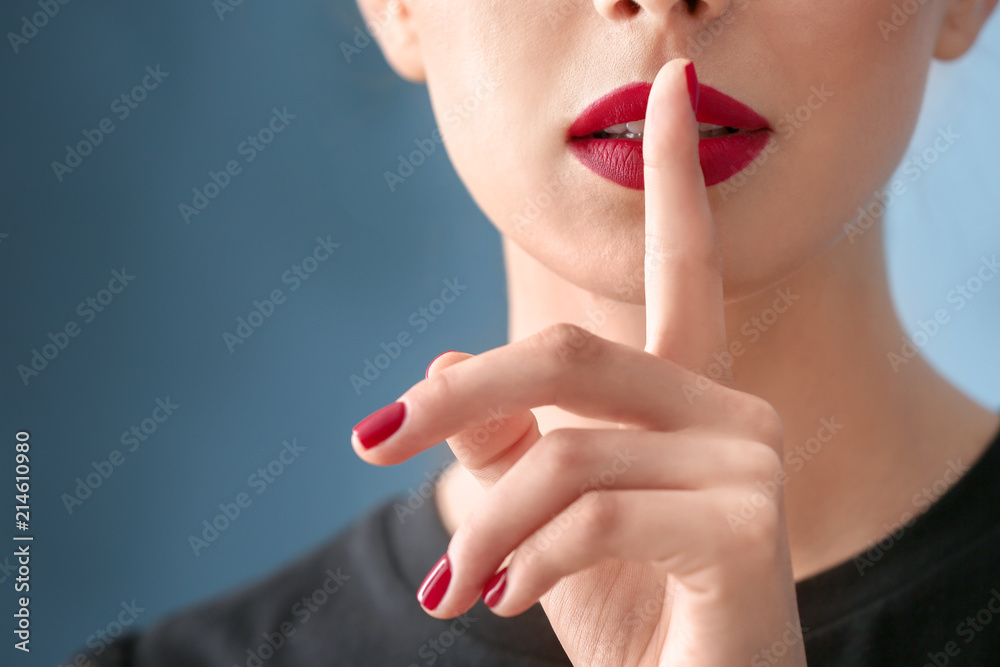 Canvas Prints Young woman with beautiful manicure showing silence gesture on color background, closeup