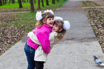 Two funny siblings sister hugging with each other while walk in park. Having fun together, positive emotions, bright colors. Copy space. Back to school