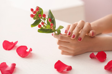 Female hands with beautiful manicure and branch on table