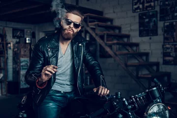 Foto op Plexiglas Young Bearded Biker in Sunglasses Smoke Cigar. © VadimGuzhva