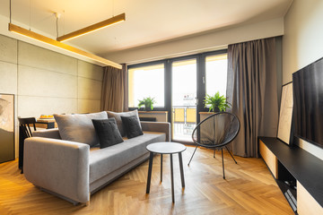 Naklejka na ściany i meble Urban style, cozy living room interior with industrial concrete walls, gray furniture and accessories and herringbone hardwood floor