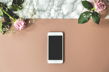 Two pink roses on top view photo of marble table with mockup phone and empty space for your product