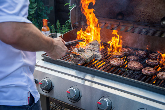 Man cooking barbecue with flames in a UK garden