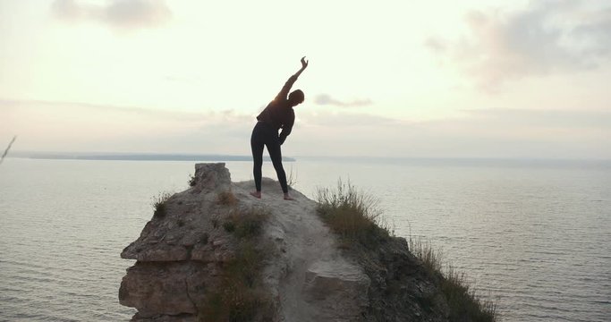 Woman doing morning warm-up on top of a cliff by the river