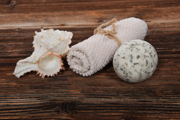 herbal white bath ball white towel and sea shell in a bathtub on a brown background
