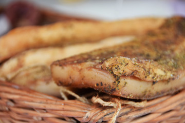 smoked bacon in paprika and lard in cubes on a stall in a wicker basket