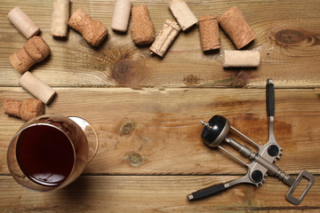 group of wine bottle cork, a glass of red wine  and a corkscrew on a wooden table with copy space for your text