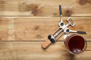 corkscrew and a glass of red wine rest on a rustic wooden board with copy space for your text