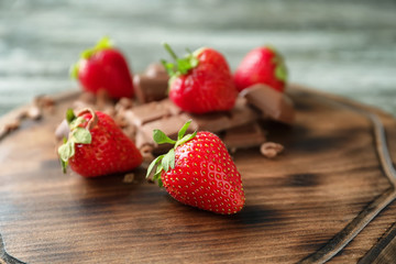 Wooden board with fresh ripe strawberries and chocolate, closeup