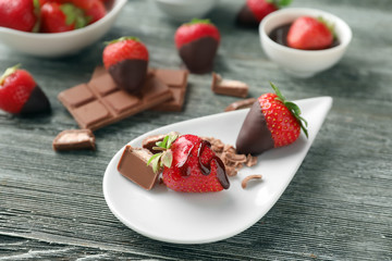 Plate with fresh strawberries and chocolate on wooden background