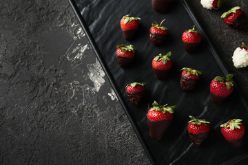 Plate with delicious strawberry covered with chocolate on grey textured background