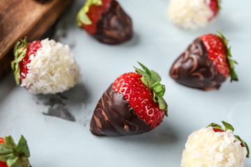 Delicious strawberries covered with chocolate on color background