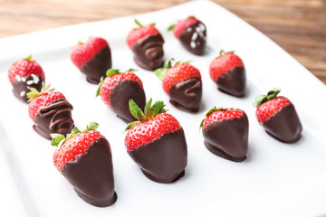 Strawberries covered with chocolate on plate, closeup