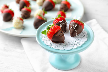 Dessert stand with delicious strawberries dipped in dark chocolate on light table