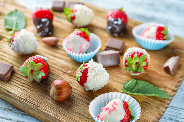 Delicious strawberries covered with chocolate on wooden board