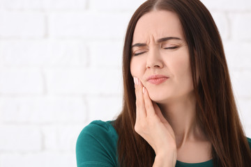 Young woman suffering from toothache on blurred background