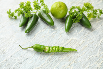 Fresh chili peppers with parsley and lime on light background