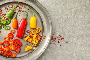 Plate with fresh and dried chili peppers on grey background