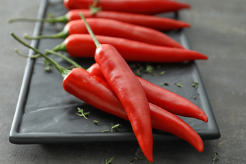 Plate with fresh chili peppers on grey background, closeup