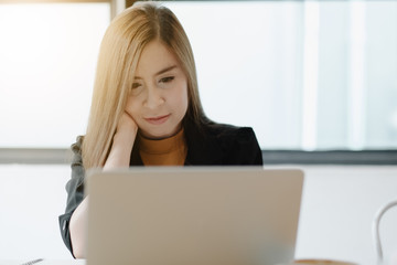 Young woman sitting in coffee shop at wooden table, drinking coffee and using laptop.On table is laptop. Girl browsing internet, chatting, blogging. Female holding laptop and looking on his screen.