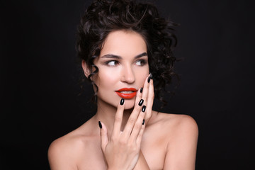 Fashionable young woman with black manicure on dark background