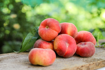 Ripe fresh juicy fig peaches with leaves on a wooden board in summer garden on grean background. Summer harvesting and gardening concept. Raw natural food.