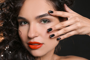 Fototapeta na wymiar Fashionable young woman with black manicure on dark background, closeup