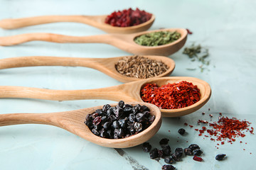 Spoons with different dry spices on color background