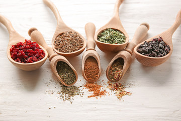 Spoons and scoops with different dry spices on wooden background