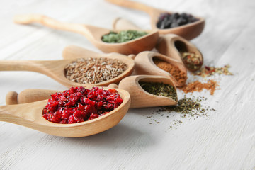 Spoons and scoops with different dry spices on wooden background