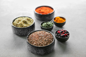 Bowls with different dry spices on light background