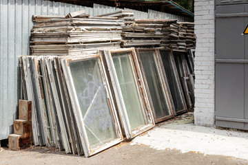 Heap of old wooden window frames with glass outdoors. Broken materials after window energy saving technology upgrade